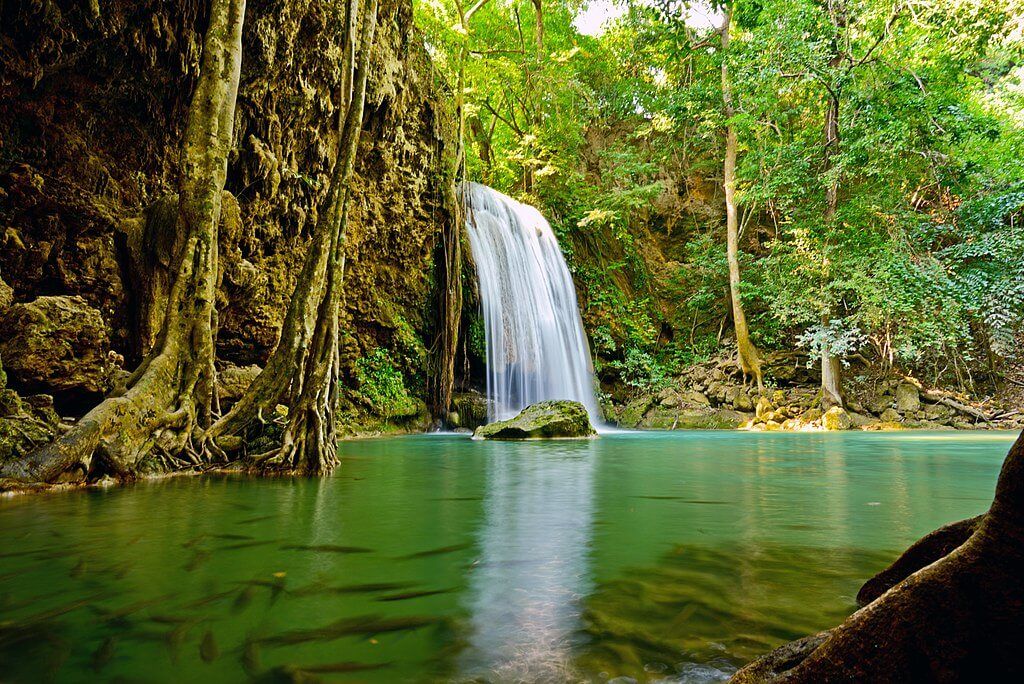 Scenic waterfall surrounded by lush green forest at Erawan National Park