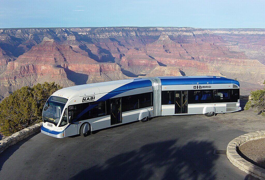 Autobús articulado híbrido estacionado en el Gran Cañón con vistas panorámicas.