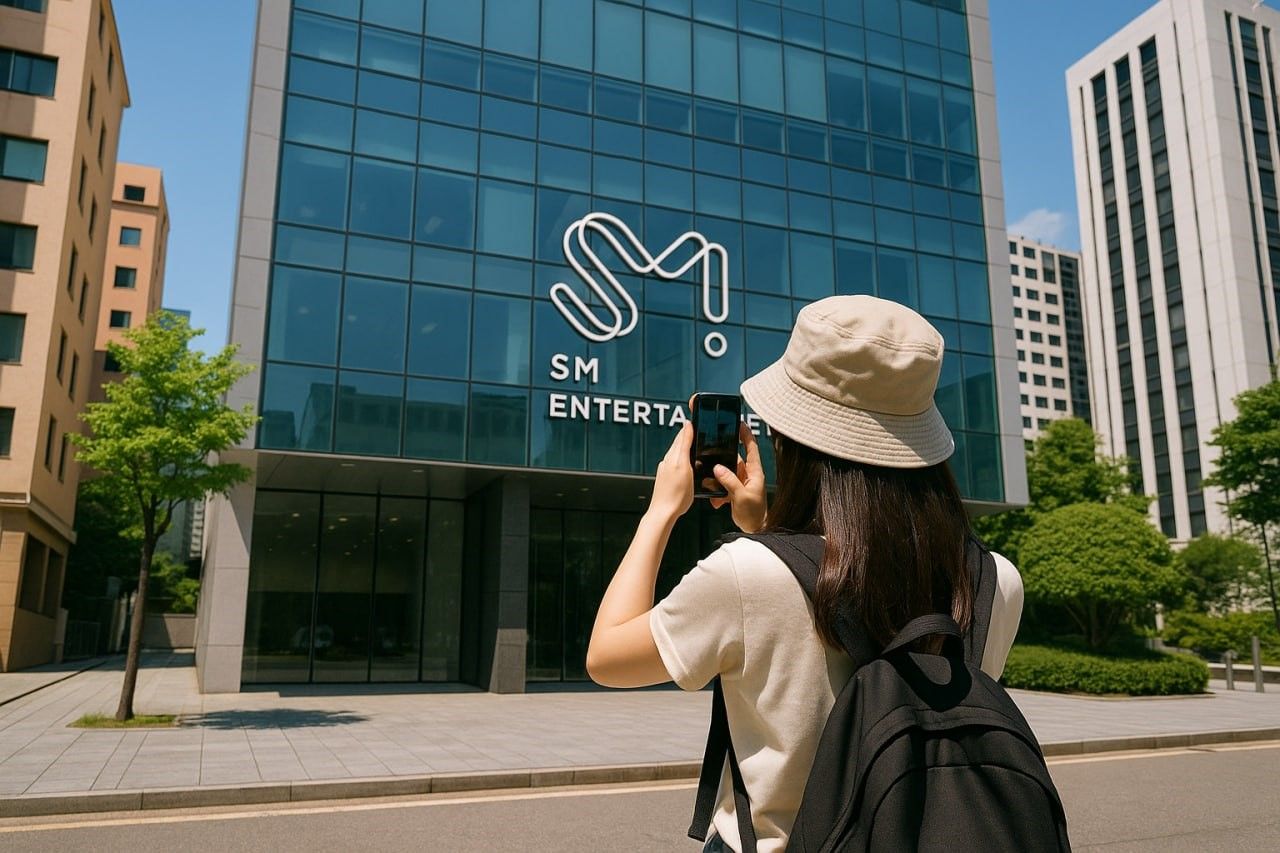 A fan standing outside a major Seoul entertainment building taking photos with a smartphone