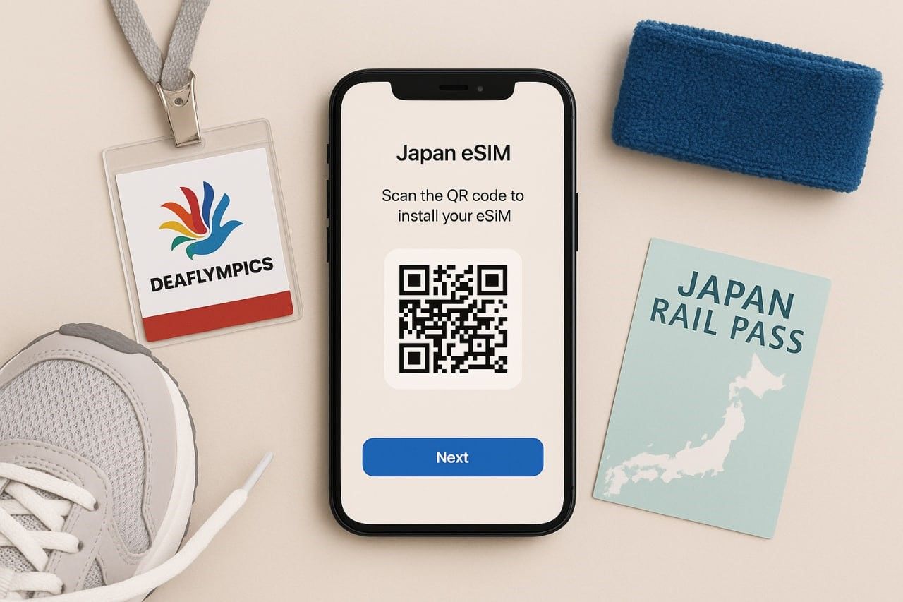 A clean, top-down scene showing a smartphone displaying a Japan eSIM QR setup screen, surrounded by travel essentials like a Deaflympics badge