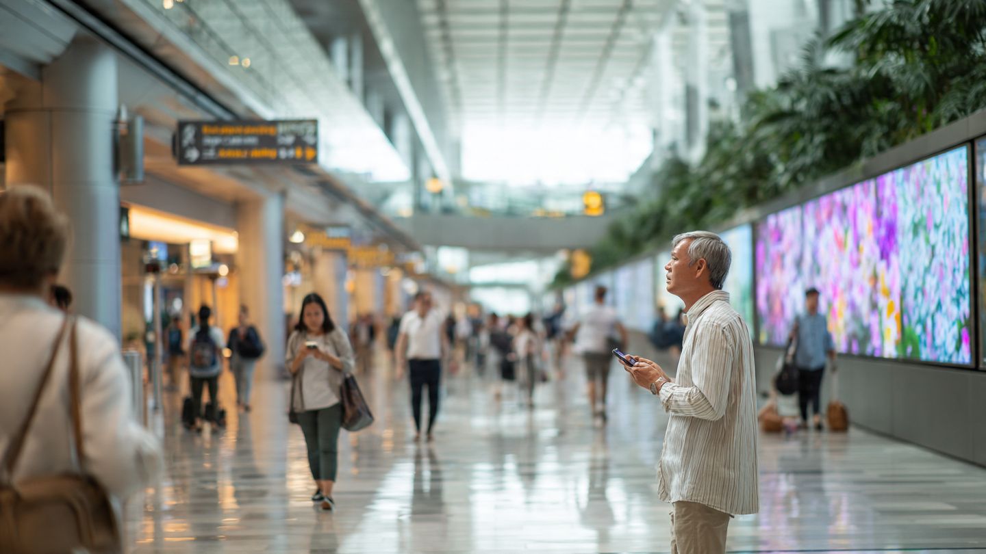 A bright, modern scene inside Singapore Changi Airport with travelers using phones, digital signage in background, showcasing effortless eSIM connectivity with a clean, travel-tech atmosphere