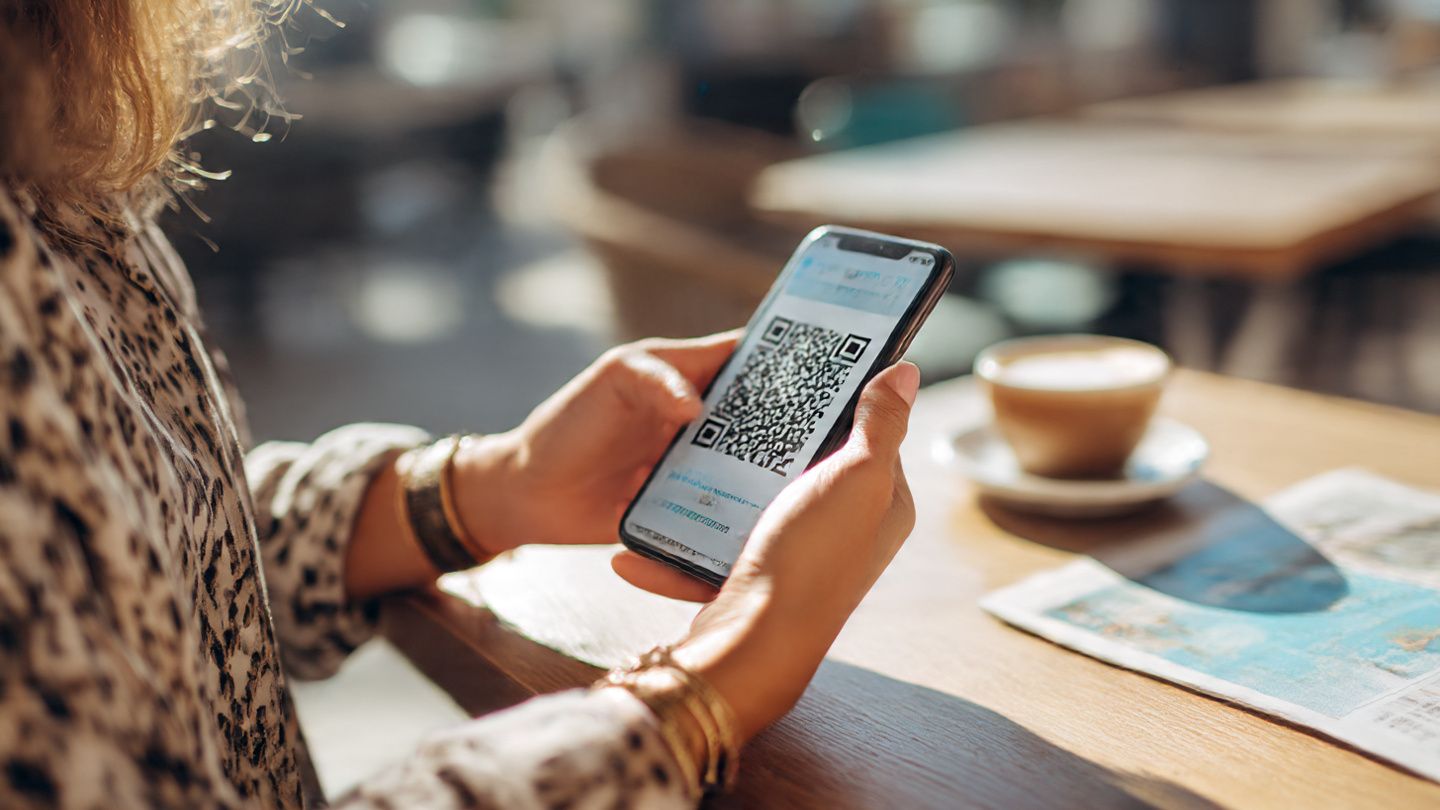 A close-up travel lifestyle image of a traveler scanning an eSIM QR code on their smartphone at a café in Lisbon; bright, modern, friendly, informative tone meant to illustrate easy activation