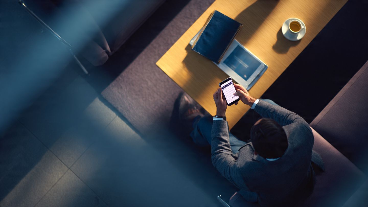 A detailed overhead shot of a business traveler installing an eSIM on their smartphone at an airport lounge, in soft natural lighting with a professional, tech-focused atmosphere