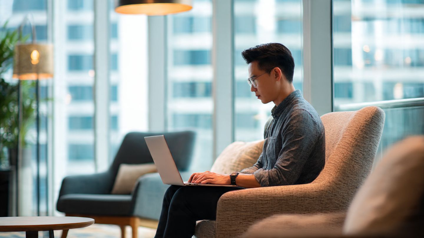 A professional traveler working on a laptop in a modern co-working space in Singapore, natural daylight, representing reliable digital access through Asia multi-country eSIMs