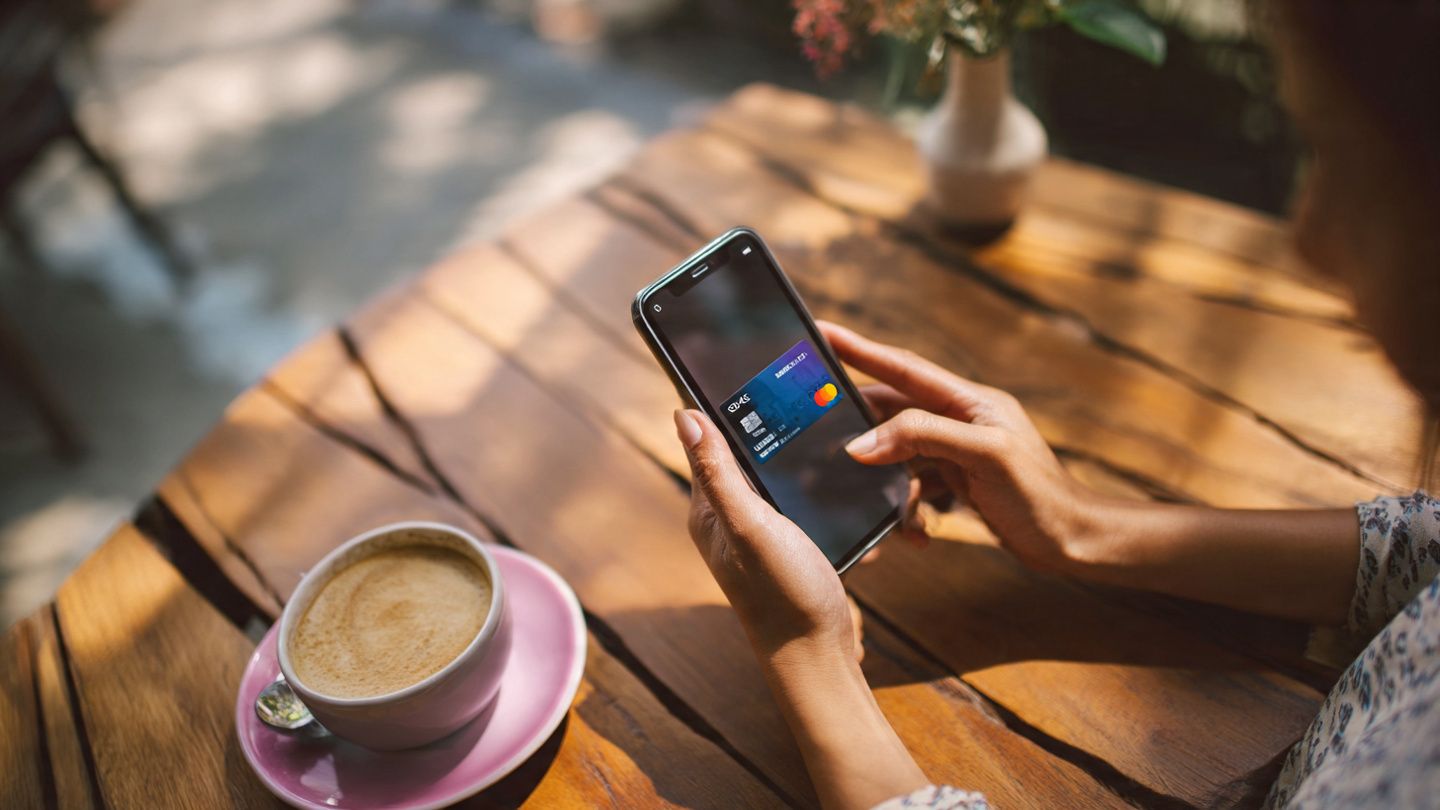 Overhead view of a traveler activating an eSIM on their phone in a Cambodian café; soft daylight; device-focused; cybersecurity and travel safety visual theme