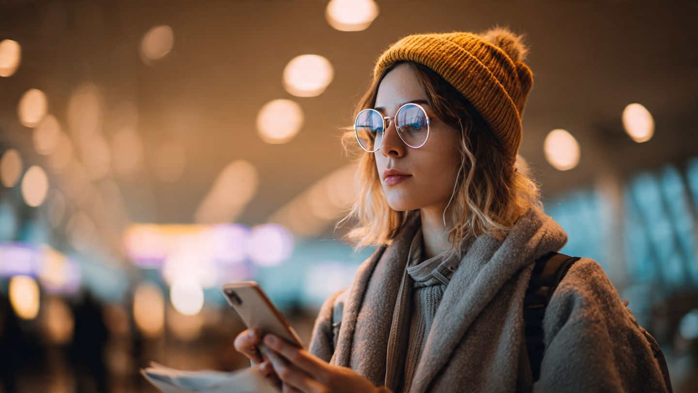 A traveler at Larnaca Airport holding a smartphone while reviewing conference documents; soft warm lighting; instructional connectivity guide