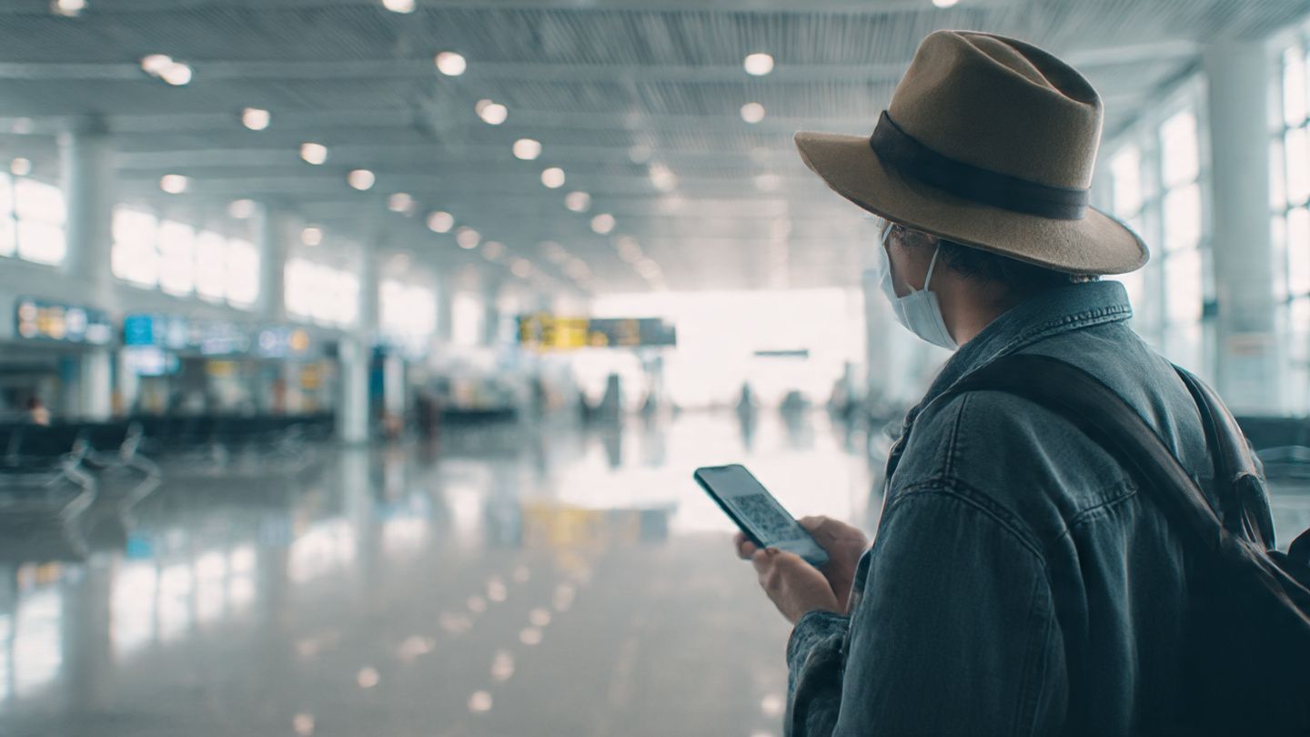 A traveler at Nội Bài International Airport scanning a QR code on a smartphone to activate an eSIM, bright daylight terminal lighting, minimalistic tech-focused composition