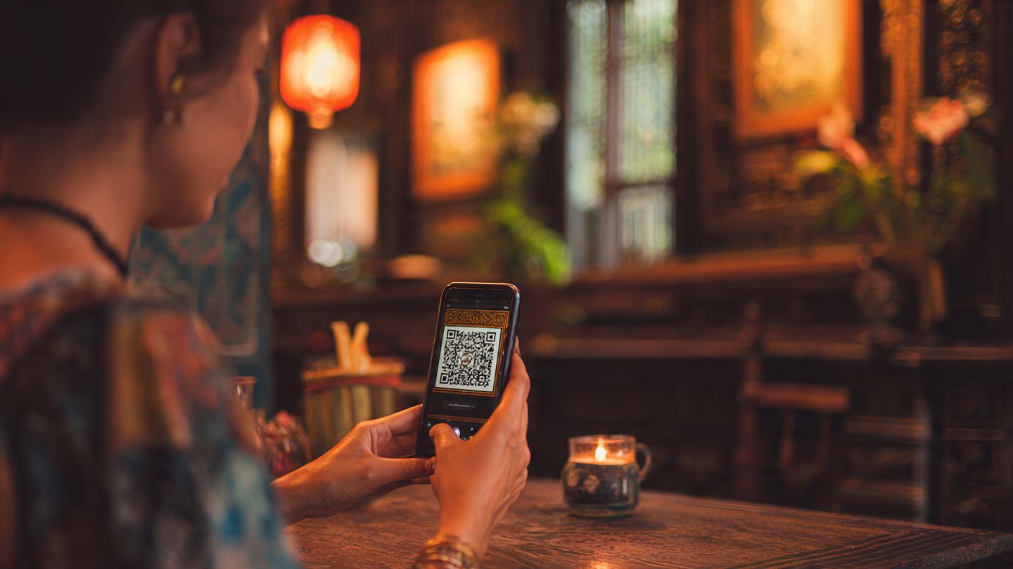 A traveler scanning a QR code to activate an eSIM in a cozy Hanoi café near the Old Quarter, warm tones, digital lifestyle photography — purpose: demonstrate easy travel setup
