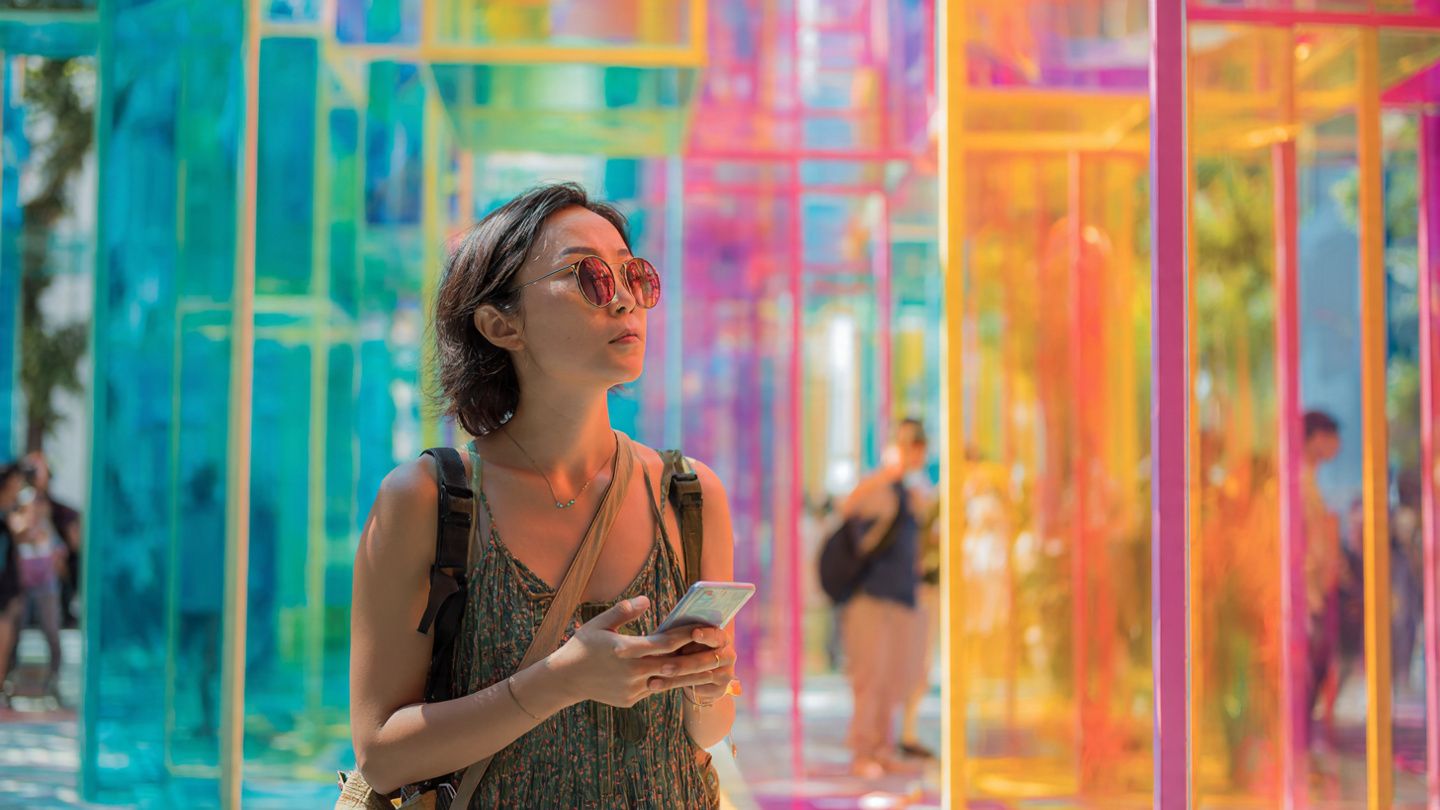 A creative overhead shot of a traveler using a phone to navigate between art galleries in Singapore; modern architecture, bright daylight, editorial travel style