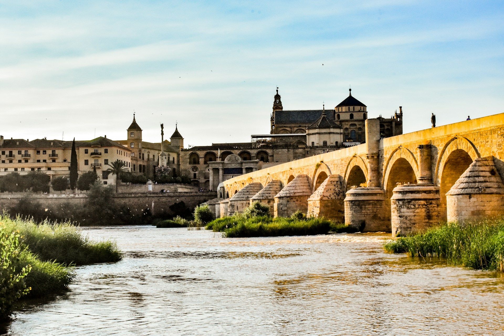 The Roman bridge over a river with a castle in the background
