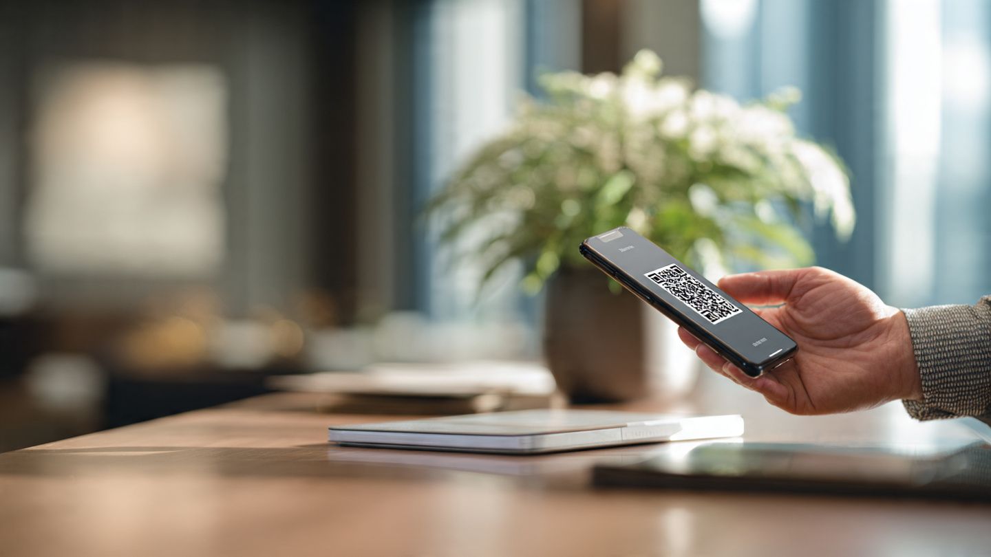 Close-up of executive scanning an eSIM QR code on smartphone at hotel desk, soft lighting, modern corporate style to illustrate effortless business setup
