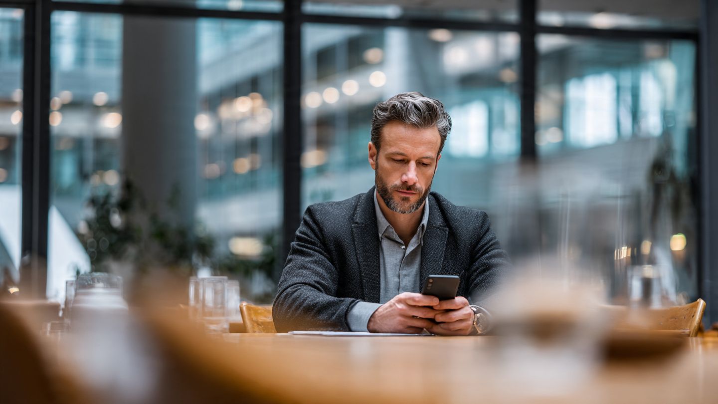 Corporate traveler seated at conference center table, reviewing notes on a 5G-connected smartphone, professional atmosphere, designed to emphasize productivity and seamless data usage