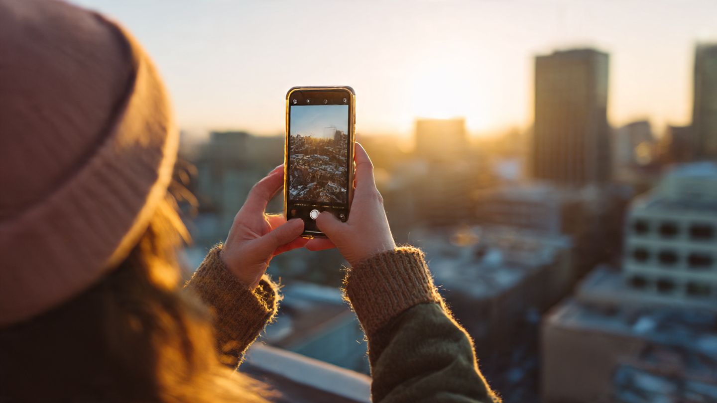 Creator recording an Instagram Story on a city rooftop abroad, golden hour lighting, smartphone close-up, modern travel influencer aesthetic focusing on seamless data connection