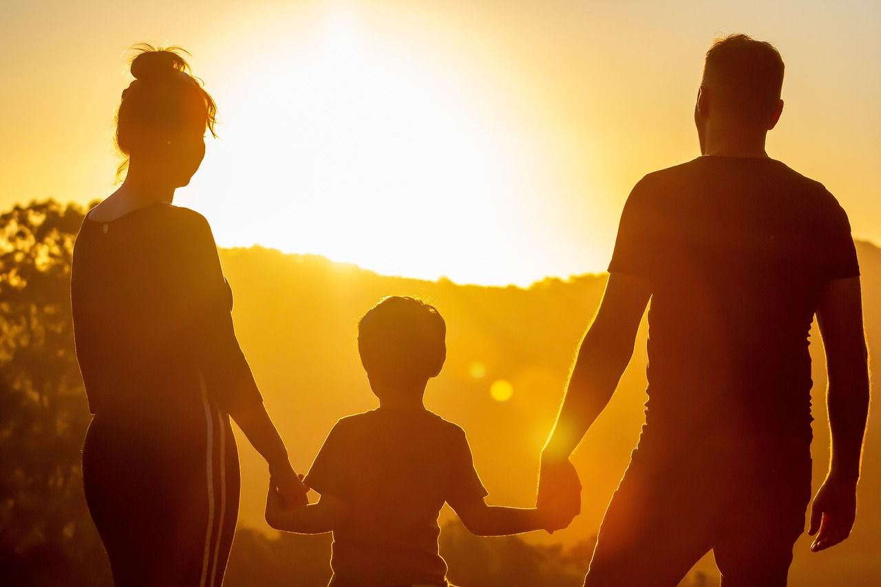 Una familia tomada de la mano, silueteada contra un vibrante atardecer