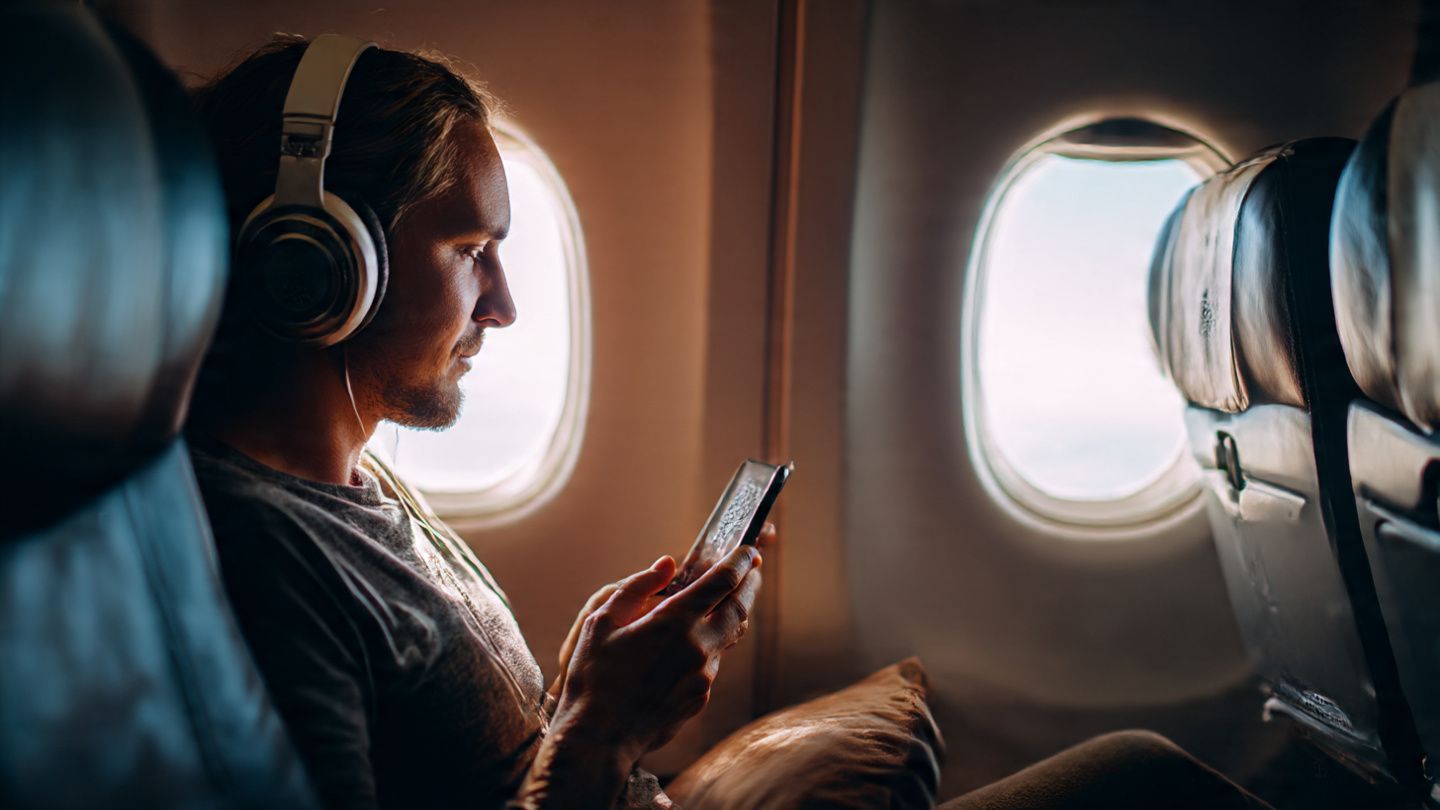 Fan sitting in airplane seat wearing headphones, scanning a QR eSIM code on a smartphone; calm travel prep mood; educational tech-travel scene