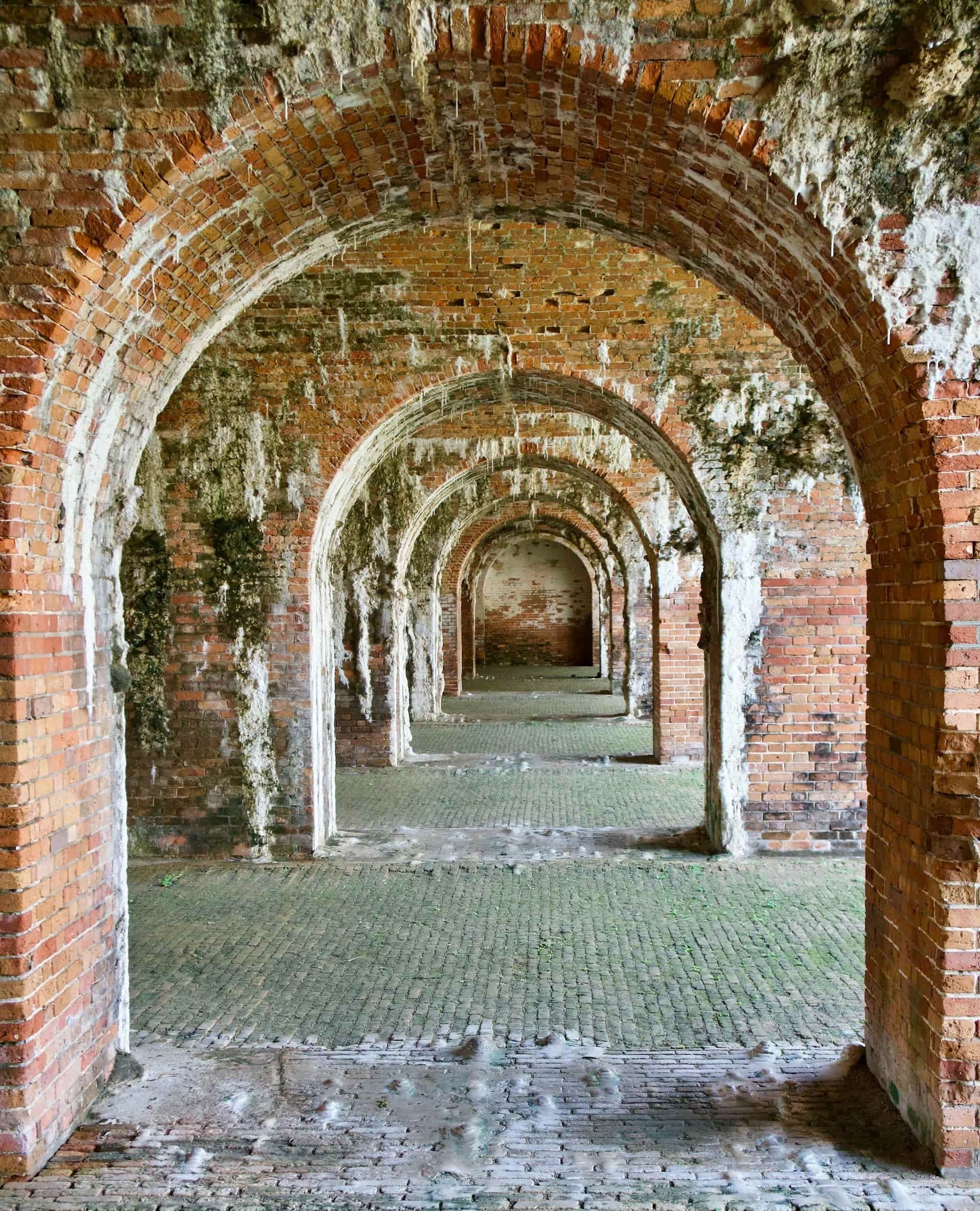 A series of rustic brick arches covered in moss and aged textures in an old structure.
