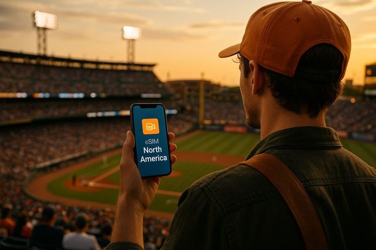 Traveler holding a smartphone with an active North America eSIM, overlooking a baseball stadium during golden hour