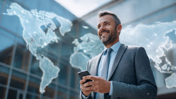 A confident real estate agent standing outside an international property while managing listings on a smartphone, symbolizing global business connectivity — modern, professional, optimistic scene.