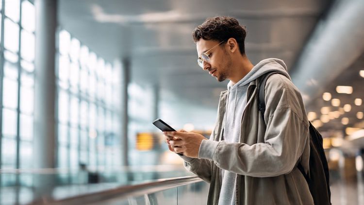 A traveler comparing discounted eSIM travel plans on a smartphone during Black Friday in a bright airport lounge; modern, clean, promotional tone