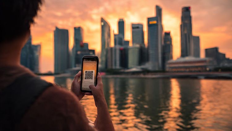 A traveler holding a smartphone showing an eSIM QR code while overlooking the Singapore skyline at sunset, cinematic lighting, smooth travel-tech aesthetic, intended for an article about Canada–Singapore connectivity