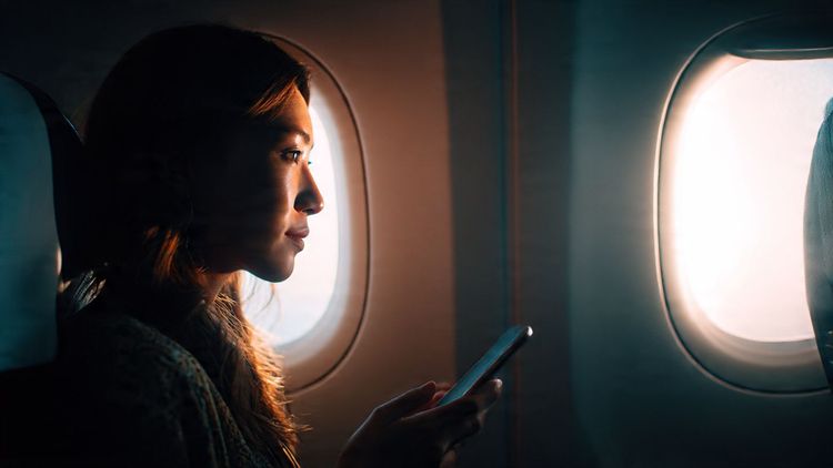 A traveler looking out an airplane window on a Singapore Airlines flight, holding a phone prepared with an eSIM; bright, cinematic, premium travel style