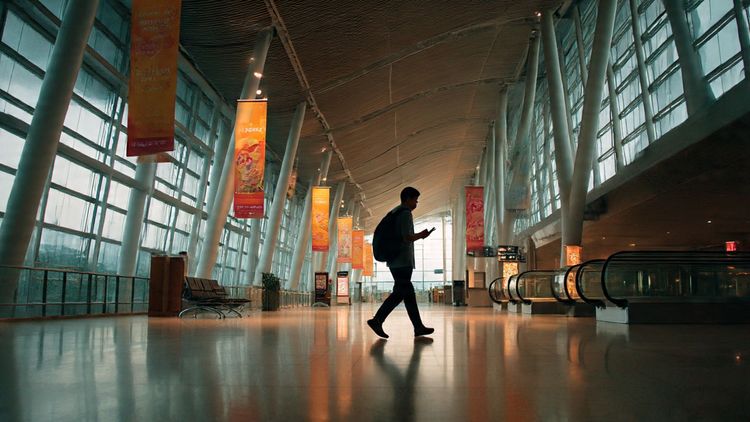 A traveler walking through an ASEAN airport terminal with digital maps on their phone, modern lighting, summit banners, and a clear focus on staying connected throughout Southeast Asia; cinematic, warm, informative