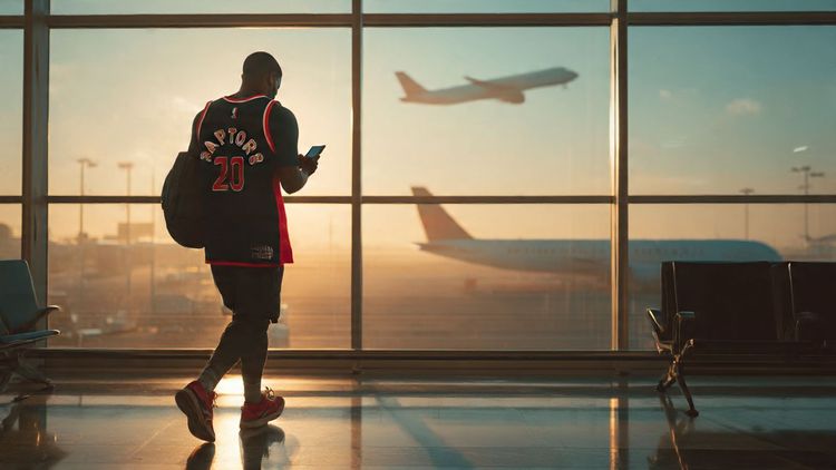 A traveler walking through Toronto Pearson Airport with an NBA jersey, smartphone in hand, looking at a digital eSIM QR code while a plane prepares for takeoff — cinematic, warm travel photography, emphasizing seamless connectivity