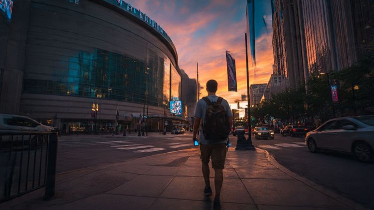 A traveler walking toward the Wells Fargo Center in Philadelphia at sunset, with a smartphone in hand showing an active digital eSIM; cinematic wide-angle shot, vivid colors, travel-tech tone