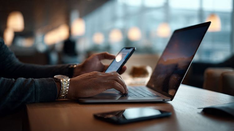 A traveler working from a laptop in an airport lounge, with a smartphone showing an active private eSIM connection; soft lighting, modern travel aesthetic, clean and secure mood