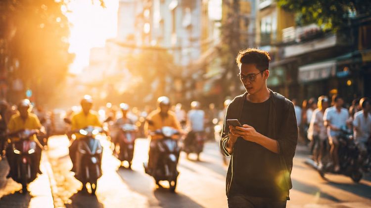 Business traveler walking in Ho Chi Minh City with smartphone in hand, checking eSIM data plans; early morning light; dynamic street energy