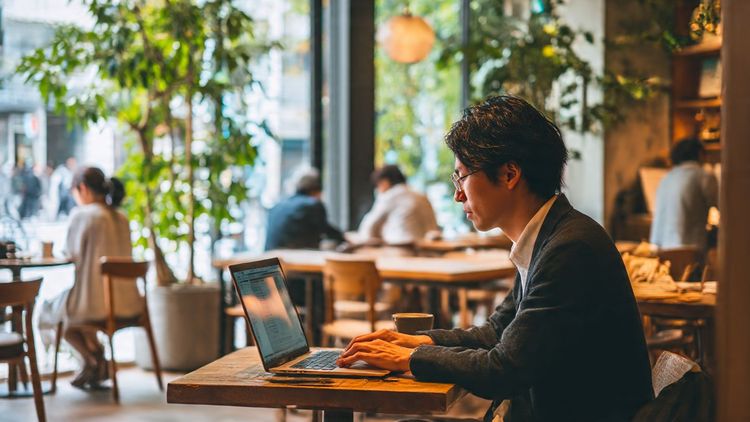 Digital nomad in Tokyo café using laptop for remote tax filing — professional, calm, and productivity-oriented scene