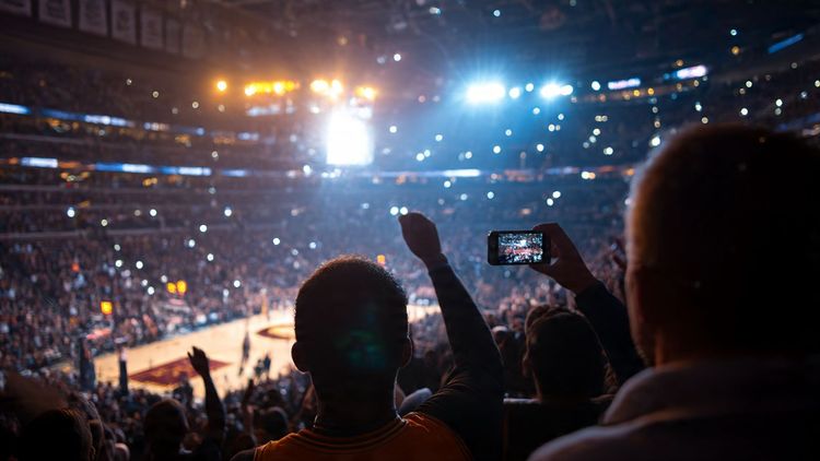 Fans cheering courtside at an NBA arena, bright stadium lights, Detroit vs Cleveland theme, travel photography mood, wide angle perspective, capturing excitement and smartphones in hand