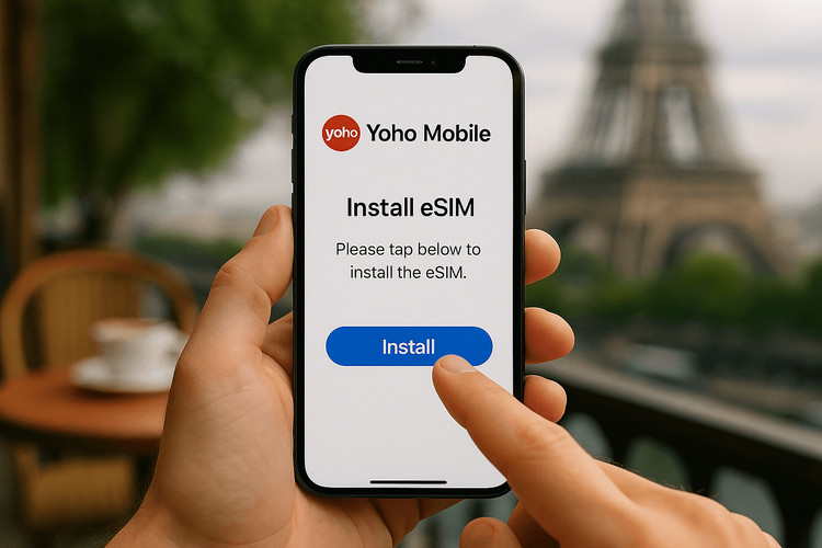 A person installing a Yoho Mobile eSIM on their smartphone with a Parisian cafe in the background.