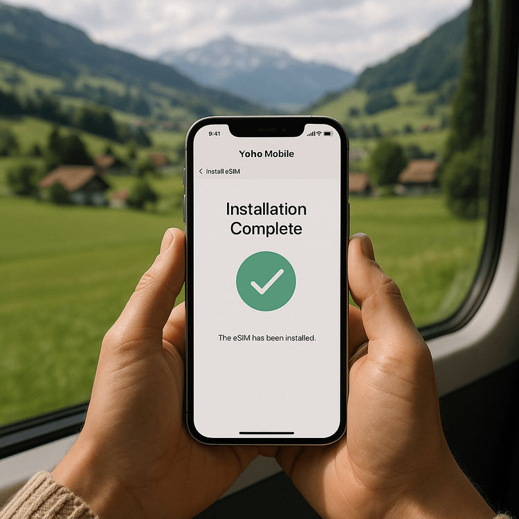 Close-up of an iPhone screen showing the successful installation of a Yoho Mobile eSIM, with the Swiss countryside visible in the background.