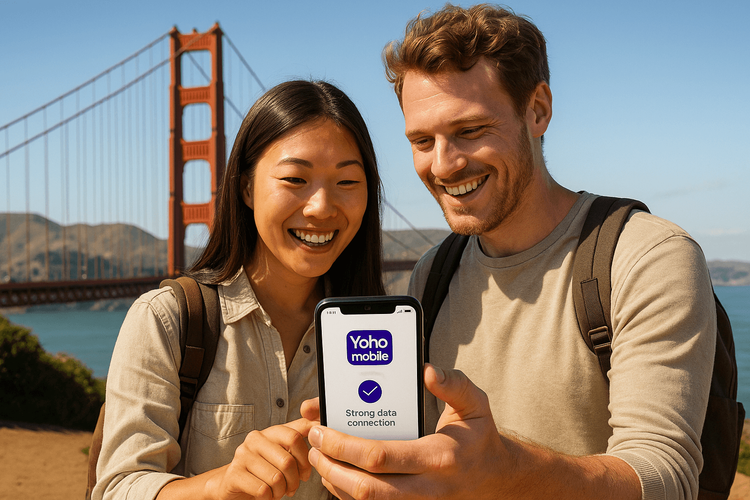 Happy international travelers using a Yoho Mobile eSIM on their phone with the Golden Gate Bridge in the background.