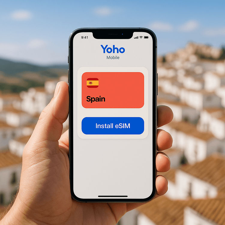 A user holding an iPhone showing the simple 'Install eSIM' button in the Yoho Mobile app, with a scenic Andalusian village in the background.