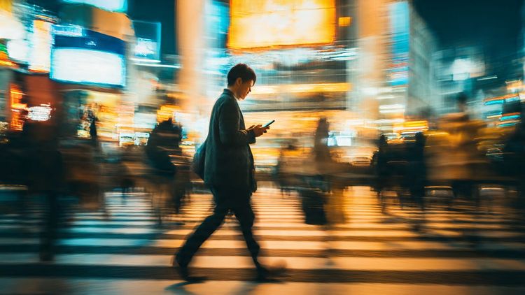 Traveler walking through Tokyo’s Shibuya Crossing using a phone with bright city lights in motion; energetic, modern, tech-forward travel mood