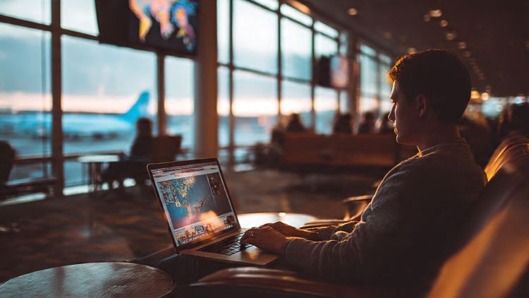 Traveler watching international news on a laptop in a cozy airport lounge, soft natural lighting, global travel mood