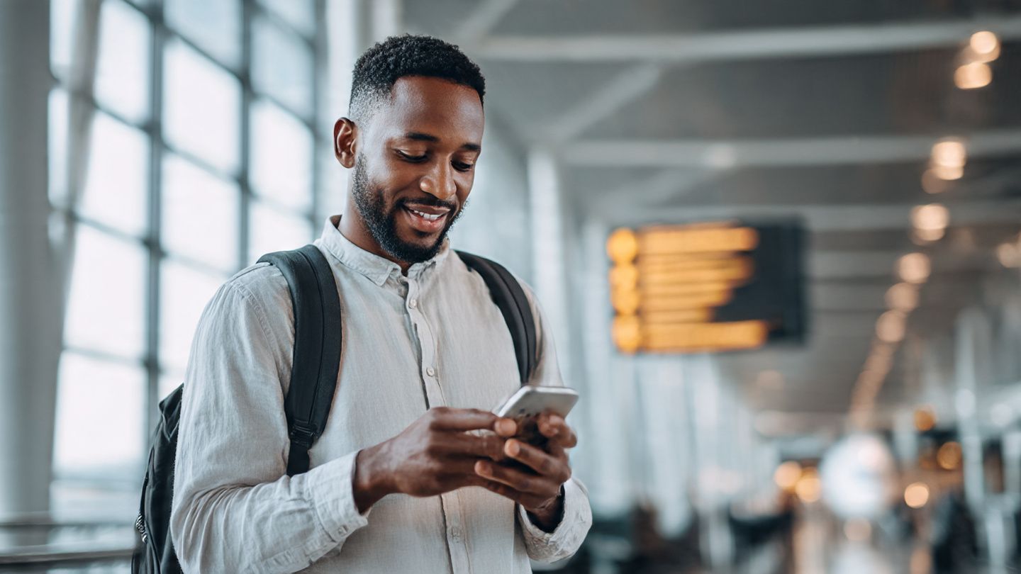 Traveler scanning a QR code on a smartphone to activate an international eSIM before boarding – clean airport background, bright lighting, relaxed travel mood.