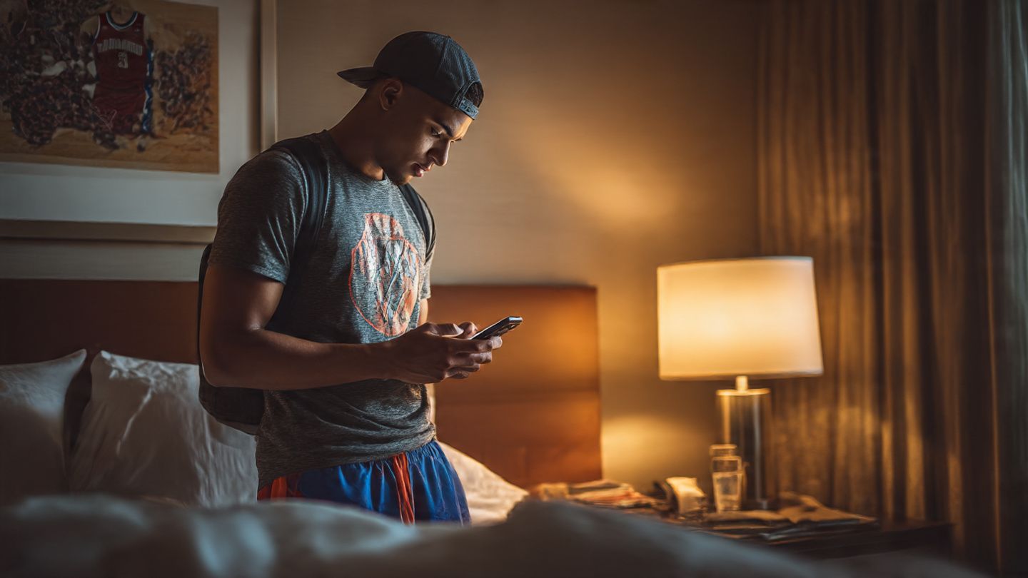 Traveler scanning an eSIM QR code in a hotel room in New Orleans before heading to the Celtics vs. Pelicans game — realistic lifestyle image, warm lighting, sports fan energy