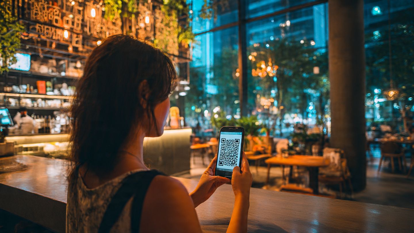 Traveler scanning eSIM QR code at a modern café in Ho Chi Minh City; vibrant urban vibe; warm lighting; business and leisure mix
