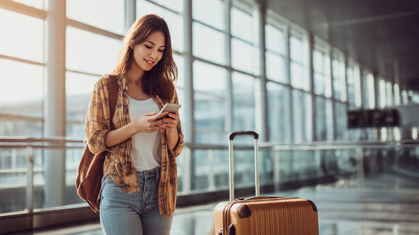 Traveler scanning QR code on phone at airport with suitcase, representing easy eSIM setup for NBA All-Star travel – bright, modern, connected vibe