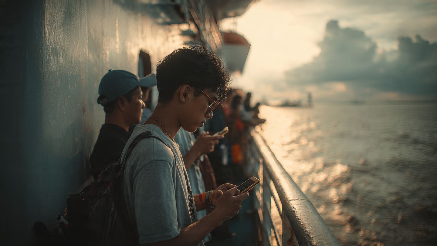 Travelers checking their phones on a ferry deck between Batam and Singapore; soft ocean light, editorial photography style